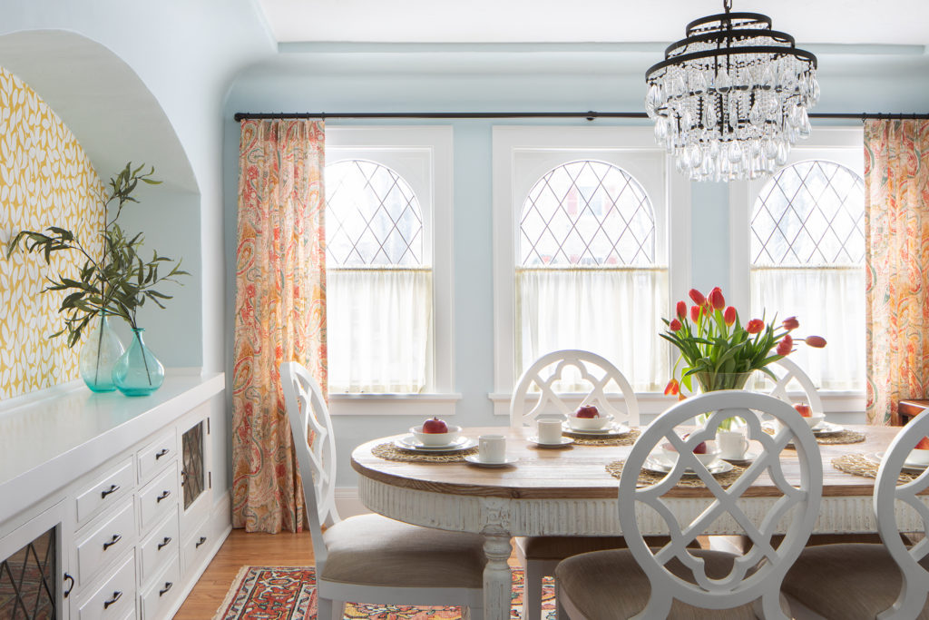 A great example showing how the wallpaper in this vintage home shows off the curved archway over antique built-ins.